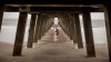 Danny James walks under the Tybee Island pier with a hat full of sea shells he collected during low tide as Hurricane Dorian passes 80 miles out to sea, Thursday, Sept. 5, 2019, in Tybee Island, Ga. Re-energized at 115 mph, Hurricane Dorian raked the Southeastern U.S. coast with howling, window-rattling winds and sideways rain Thursday, knocking out power to more than 200,000 homes and businesses as it pushed northward toward North Carolina's dangerously exposed Outer Banks. (AP Photo/Stephen B. Morton)