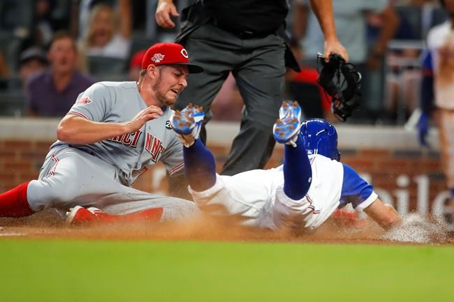 Cincinnati Reds starting pitcher Trevor Bauer, left, tags out Atlanta Braves Ender Inciarte, right, at home in the fourth inning of a baseball game, Saturday, Aug.3, 2019, in Atlanta. (AP Photo/Todd Kirkland)