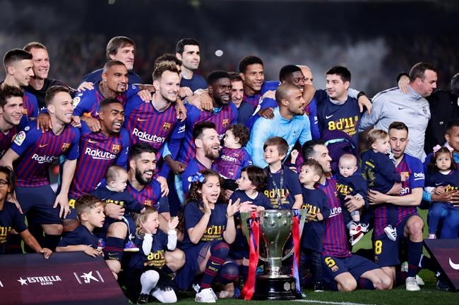 FC Barcelona players, with their children, pose with their trophy after winning the Spanish League title, at the end of the Spanish La Liga soccer match between FC Barcelona and Levante at the Camp Nou stadium in Barcelona, Spain, Saturday, April 27, 2019. Barcelona clinched the Spanish La Liga title, with three matches to spare, after it defeated Levante 1-0. (AP Photo/Manu Fernandez)