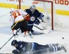 JOHN WOODS / The Canadian Press 
Calgary Flames' Mason Raymond, left, (21) leaps over Winnipeg Jets' Tyler Myers (57) as goaltender Ondrej Pavelec (31) saves his shot.