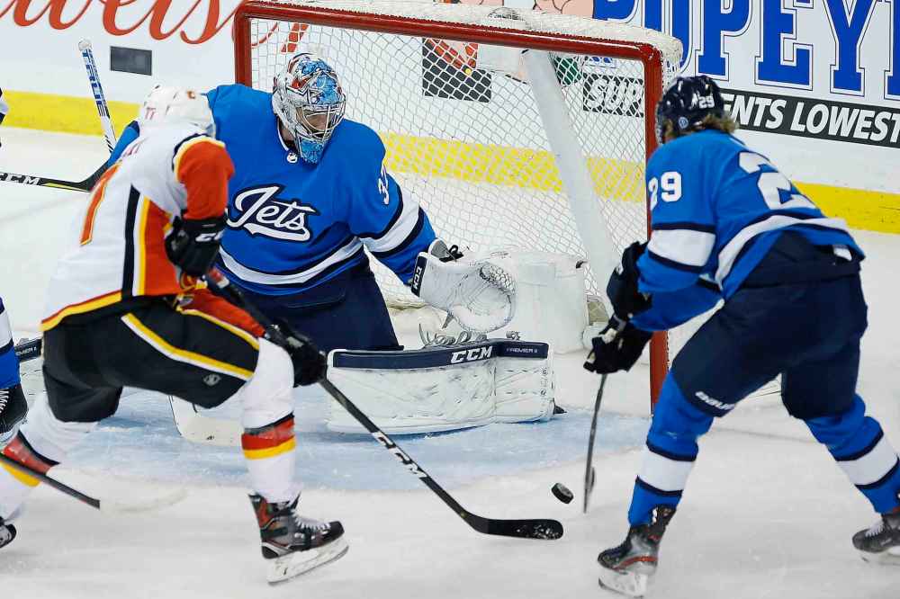 JOHN WOODS / THE CANADIAN PRESS
Winnipeg Jets goaltender Connor Hellebuyck (37) saves the shot by Calgary Flames' Mark Jankowski (77) during first period NHL action.
