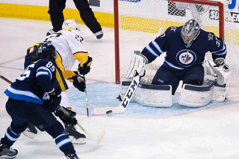 CP
Winnipeg Jets goaltender Connor Hellebuyck (37) makes the save on Nashville Predators' Kevin Fiala (22) as Jets' Mathieu Perreault (85) defends during first period NHL playoff action in Winnipeg on Monday, May 7, 2018. THE CANADIAN PRESS/John Woods