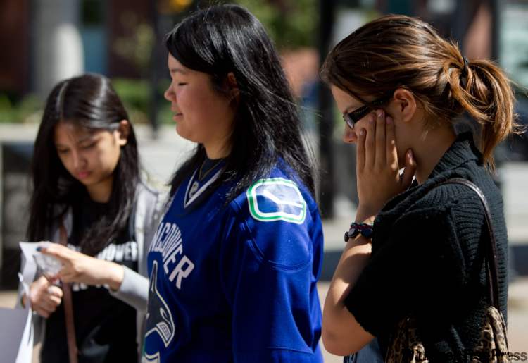 Darryl Dyck / the canadian press
People pause at a memorial for former Canucks player Rick Rypien outside Rogers Arena in Vancouver on Tuesday. Rypien was found dead at his home on Monday.