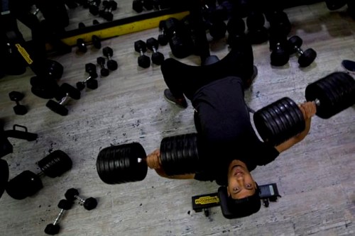 In this Sunday, May 26, 2019 photo, a Palestinian lifts weights at Techno-Gym in Gaza City. The Gaza Strip has a booming nocturnal gym scene that comes alive past midnight during the holy Islamic month of Ramadan, catering to Palestinians ready to reform their Ramadan routine. Besides self-discipline and prayer intended to bring adherents closer to God, the month is famed for its lavish meals and heavy desserts that follow a daylong fast, fueling weight-gain concerns among a growing group of middle-class men in the Palestinian enclave. (AP Photo/Hatem Moussa)
