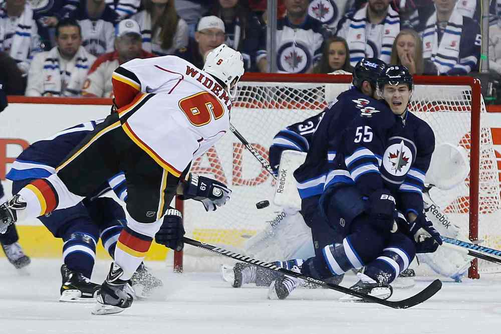 JOHN WOODS / WINNIPEG FREE PRESS
Calgary’s Dennis Wideman gets the Flames on the board in the second, blasting a puck past Winnipeg Jets goaltender Ondrej Pavelec as Mark Scheifele (55) tries in vain to block the shot.