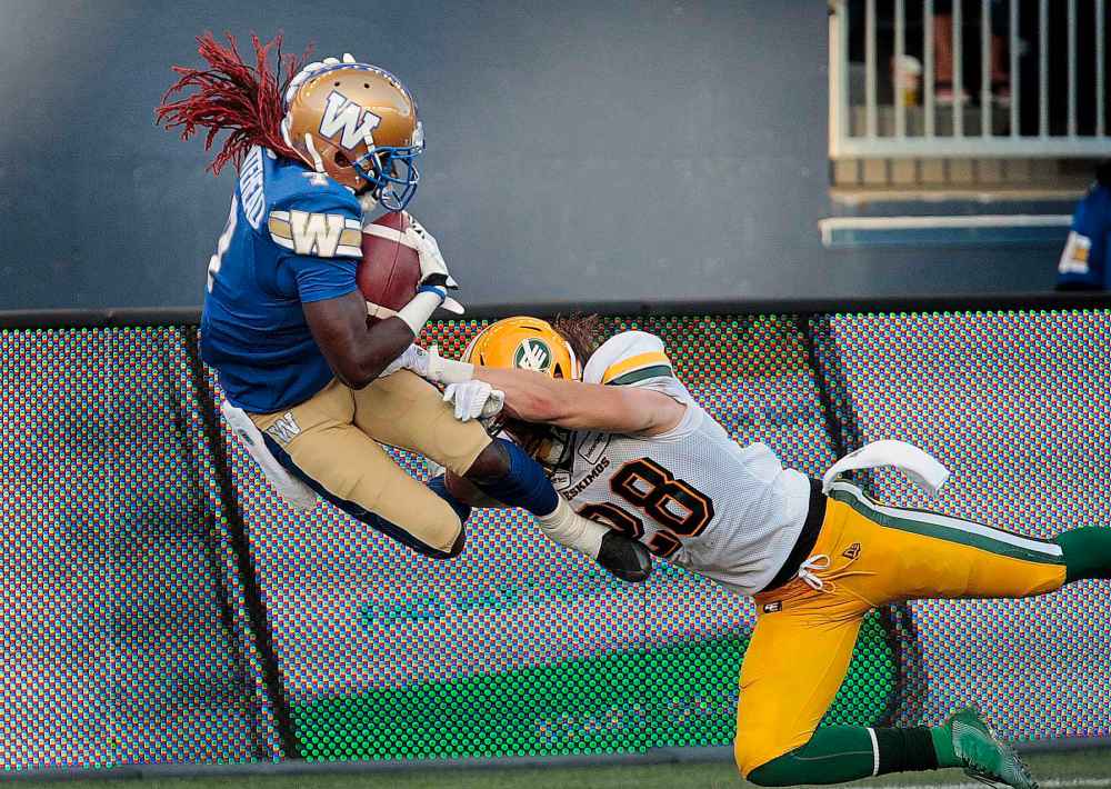 PHIL HOSSACK / WINNIPEG FREE PRESS
Winnipeg Blue Bombers' Lucky Whitehead leaps over the goal line and out of the grasp of Edmonton Eskimos' Kevin Francis to score his first CFL touchdown Thursday night at IG Field.