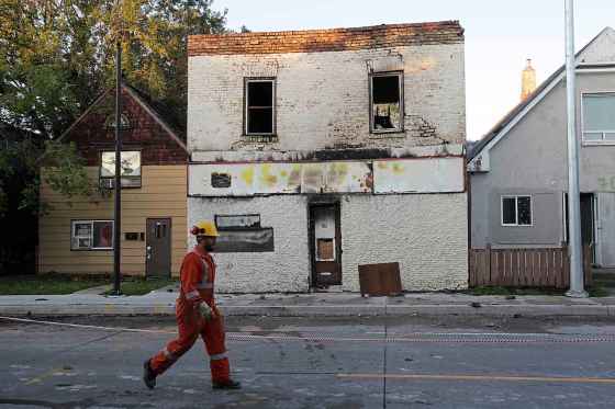 ERIK PINDERA / WINNIPEG FREE PRESSA Manitoba Hydro worker walks by the burnt-out building on Selkirk Avenue on Wednesday morning.