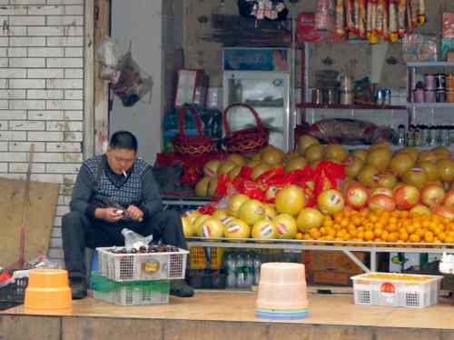 Gerald Flood / Winnipeg Free Press
A shopkeeper enjoys a puff as he prepares fruit for sale in a storefront shop in Chengdu.