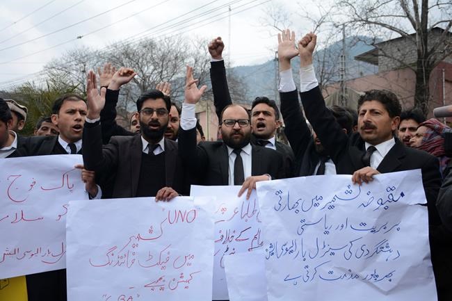 CORRECTS TRANSLATION IN BANNER - Pakistani Kashmiri lawyers hold banners during a protest in Muzafarabad, capital of Pakistani Kashmir, Tuesday, Feb. 26, 2019. Pakistan says India launched an airstrike on its territory early Tuesday that caused no casualties, while India said it targeted a terrorist training camp in a pre-emptive strike that killed a