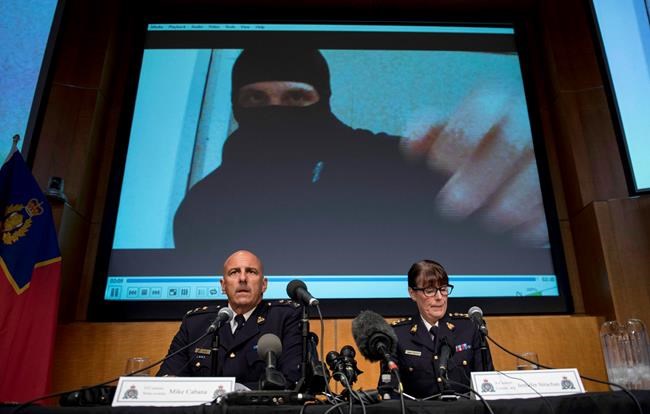 Video footage showing Aaron Driver is seen behind RCMP Deputy Commissioner Mike Cabana (left) and Assistant Commissioner Jennifer Strachan during a press conference for what the RCMP are calling a terrorism incident, in Strathroy, Ontario yesterday, on Thursday, Aug. 11, 2016 in Ottawa. THE CANADIAN PRESS/Justin Tang