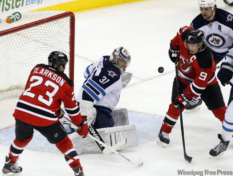 Rich Schultz / The Associated Press
Winnipeg Jets goalie Ondrej Pavelec makes a save on a shot as New Jersey Devils' David Clarkson and Zach Parise look for the rebound during the second period of their NHL game in Newark, N.J., Tuesday.