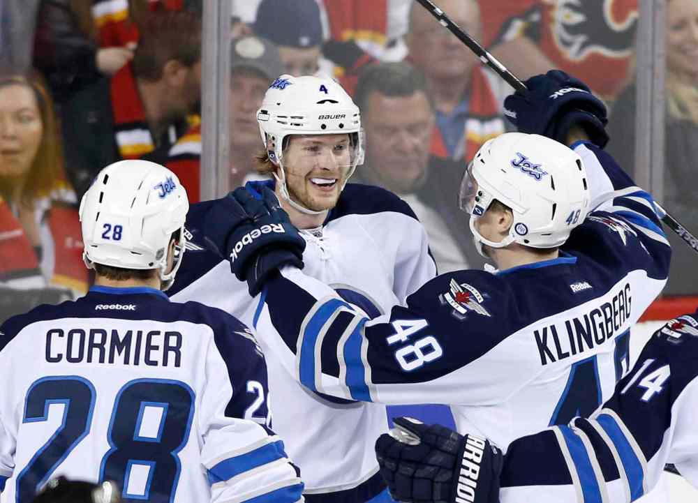 Larry MacDougal / The Canadian Press
Winnipeg Jets' Paul Postma, centre, celebrates his game-winning goal against the Calgary Flames with Patrice Cormier, left, and Carl Klingberg on Friday to end the Jets' final game of the season.