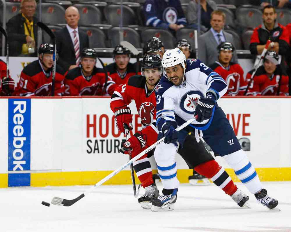Rich Schultz / The Associated Press
Winnipeg Jets defensemen Dustin Byfuglien (33) moves the puck away from New Jersey Devils center Adam Henrique (14) during the first period of an NHL hockey game in Newark, N.J., Friday night.