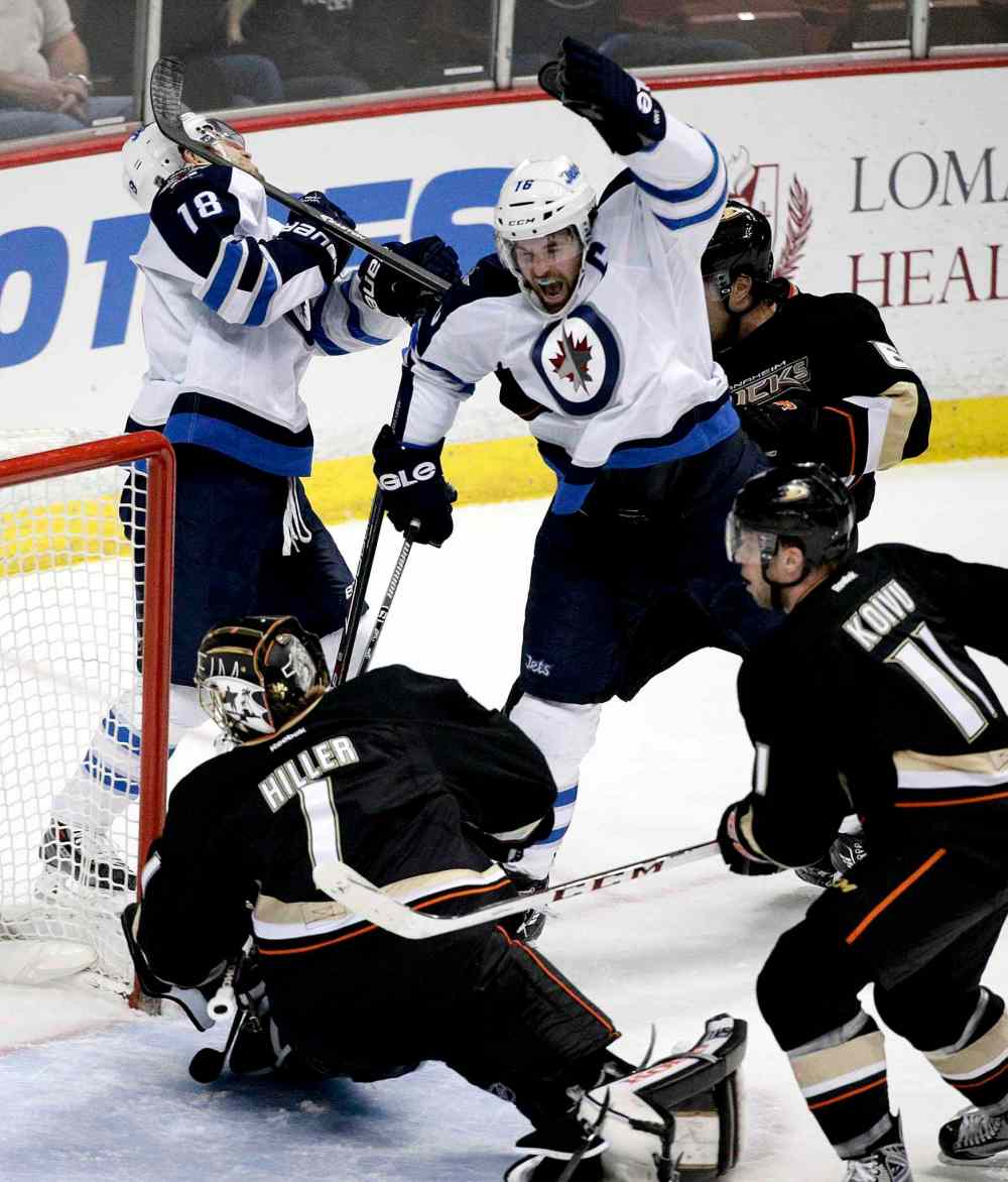 Jae C. Hong / The Associated Press
Jets' captain Andrew Ladd celebrates his first-period goal as Bryan Little gets a stick to the face. The Jets won the game 3-2.
