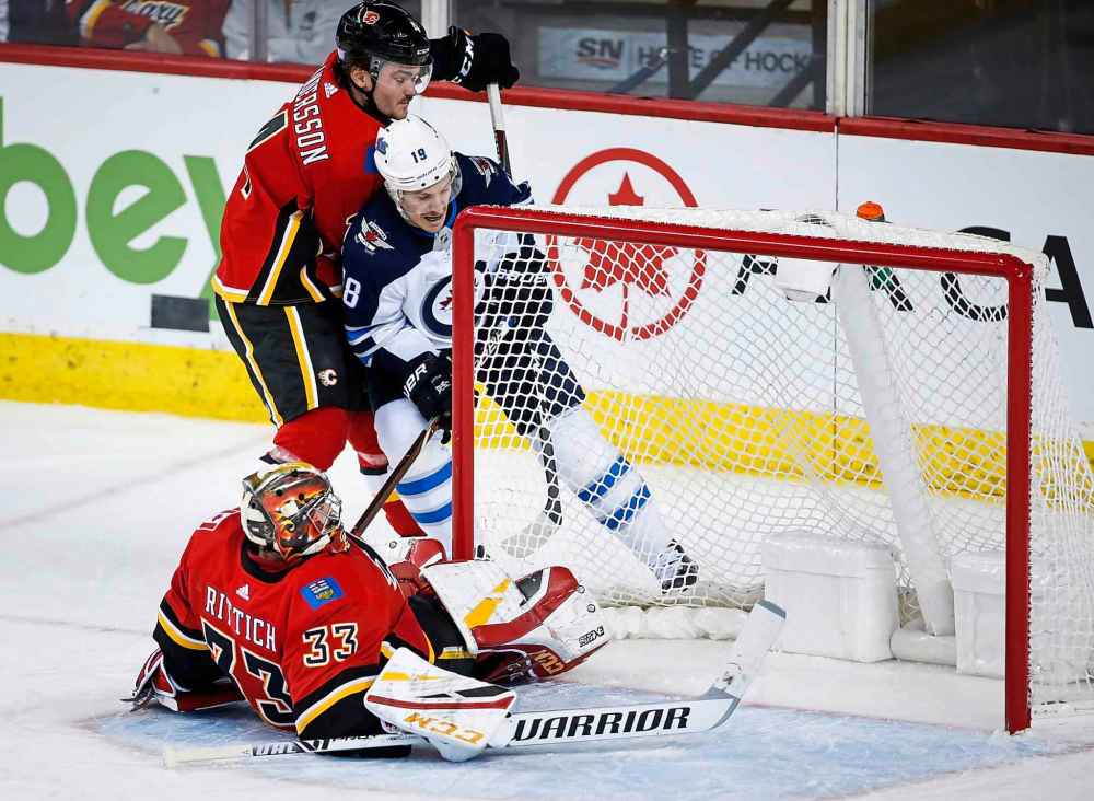 THE CANADIAN PRESS/Jeff McIntosh
Winnipeg Jets' Bryan Little, centre, hunts for the puck after Calgary Flames goalie David Rittich was knocked to the ice during the third period.