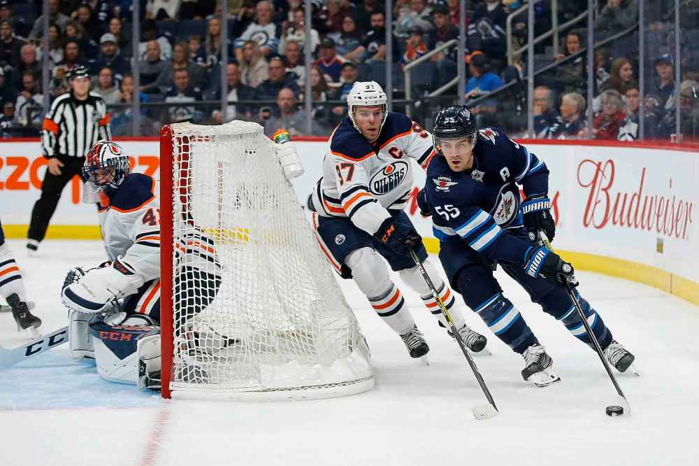 THE CANADIAN PRESS/John Woods
Winnipeg Jets centre Mark Scheifele and Edmonton Oilers centre Connor McDavid race around goaltender Mike Smith's net the during second period in Winnipeg on Thursday.