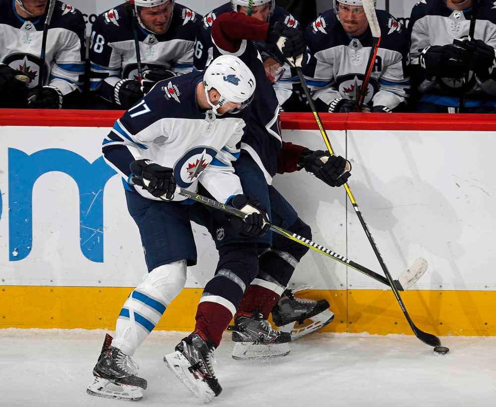 (AP Photo/David Zalubowski)
Winnipeg Jets centre Adam Lowry, left, checks Colorado Avalanche defenceman Patrik Nemeth into the team bench while fighting for control of the puck in the first period.