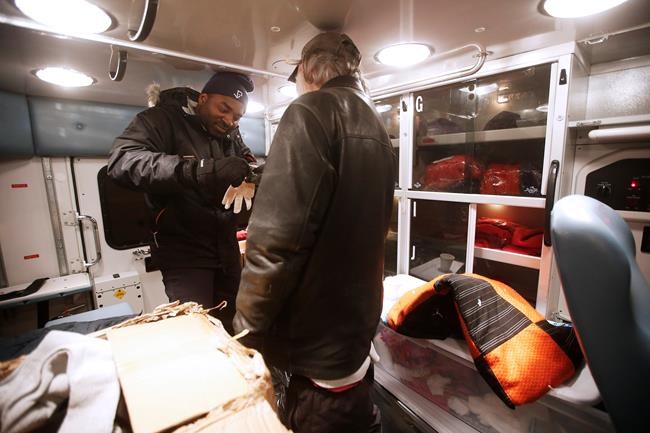 John Woods / The Canadian Press
Peter Oyeniyi (left), a van outreach worker in the Salvation Army Extreme Environment Response Vehicle, assists a man to put gloves on his frozen hands as they drive around Winnipeg streets and assists people who are suffering under the extreme temperatures in the early hours of Saturday morning, February 2, 2019.