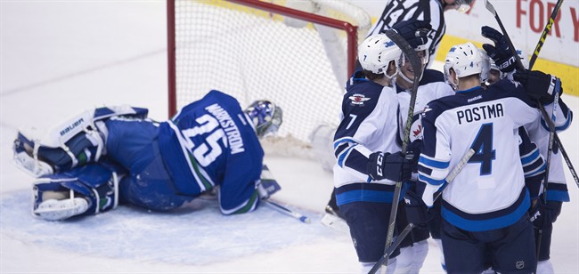 The Winnipeg Jets celebrate teammate Marko Dano's goal past Vancouver Canucks goalie Jacob Markstrom (25) during third period NHL action in Vancouver on Monday, March 14, 2016. THE CANADIAN PRESS/Jonathan Hayward
