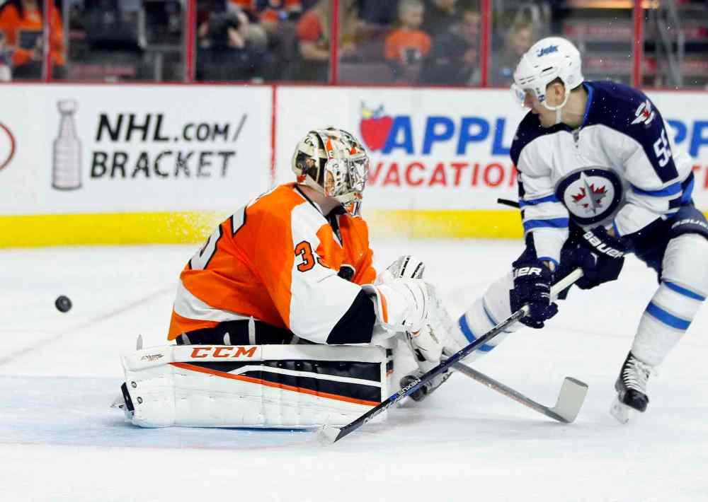 Tom Mihalek / AP
The puck goes wide of the net as Philadelphia Flyers' Steve Mason, left, fends off Winnipeg Jets' Mark Scheifele, right, during the first period of an NHL hockey game, Monday, March 28, 2016 in Philadelphia.