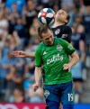 Seattle Sounders forward Harrison Shipp (19) and Sporting Kansas City defender Seth Sinovic, top, battle to control the ball during the second half of an MLS soccer match Sunday, May 26, 2019, in Kansas City, Kan. (AP Photo/Charlie Riedel)