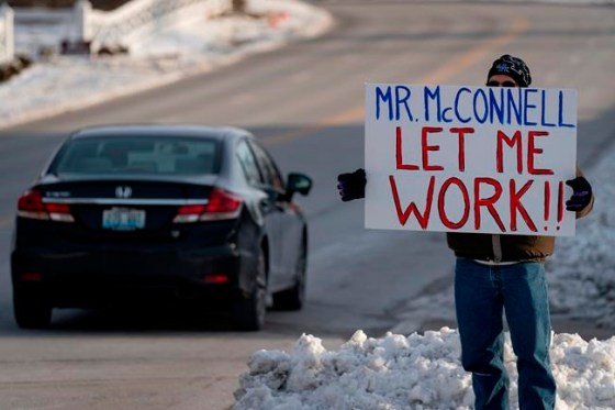 Furloughed EPA worker Jeff Herrema holds a sign outside the offices of U.S. Senator Mitch McConnell, in Park Hills, Ky., Tuesday, Jan 22, 2019. (AP Photo/Bryan Woolston)