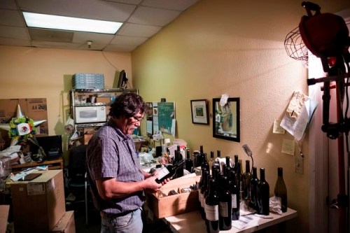 In this Aug. 25, 2017 photo provided by Quiet Pictures, veteran winemaker Gustavo Brambila hand labels one of the roughly 40,000 bottles he produces every year in Napa, Calif. 