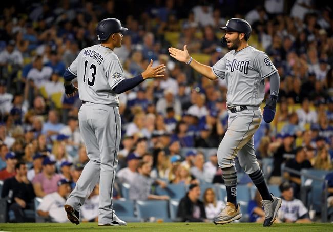 San Diego Padres' Eric Hosmer, right, is congratulated by Manny Machado as he scores on a double by Josh Naylor during the sixth inning of the team's baseball game against the Los Angeles Dodgers on Friday, Aug. 2, 2019, in Los Angeles. (AP Photo/Mark J. Terrill)