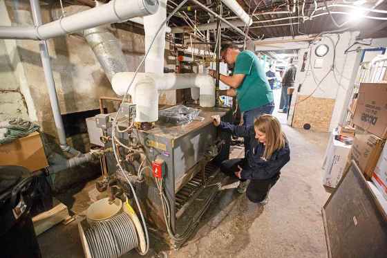 MIKE DEAL / WINNIPEG FREE PRESSBeverly Ajtay, Operations manager at Lighthouse Mission, examines the old boiler with Olaf Grundmann with G&G Heating after it was replaced with a new forced air system.