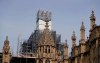 In this photo taken on Wednesday, April 17, 2019, Britain's Houses of Parliament, covered in hoarding and scaffolding as it undergoes restoration work to repair the crumbling building, in London. For some Britons who watched Notre Dame in Paris burn, horror was mixed with apprehension. What happened to the French landmark this week could befall the Houses of Parliament tomorrow. The seat of Britain's government is crumbling, leaky, infested with rodents, and a fire trap. (AP Photo/Kirsty Wigglesworth)