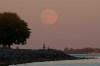 The full moon rises over Lake Ontario as people walk along the shore line in Kingston, Ont., on Monday Sept. 8, 2014. THE CANADIAN PRESS/Lars Hagberg