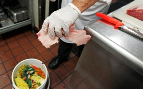 Executive chef Stephane Baloy drops beef scraps into a bucket of food waste, await to be added to the bokashi composting containers, at the Ferncroft Country Club in Middleton, Mass., Monday, June 11, 2012. The country club is among a few places in the nation trying an obscure form of composting called bokashi. Based on an ancient Japanese farming practice, food waste is covered with a mix of microorganisms, which suppress its smell and eventually composts to produce soil. (AP Photo/Charles Krupa)