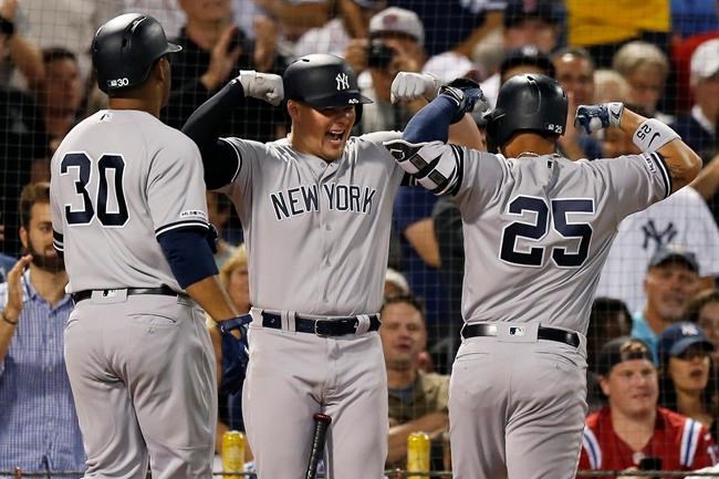 New York Yankees' Gleyber Torres (25) celebrates his two-run home with Luke Voit, center, that also drove in Edwin Encarnacion during the second inning of a baseball game against the Boston Red Sox in Boston, Sunday, Sept. 8, 2019. (AP Photo/Michael Dwyer)
