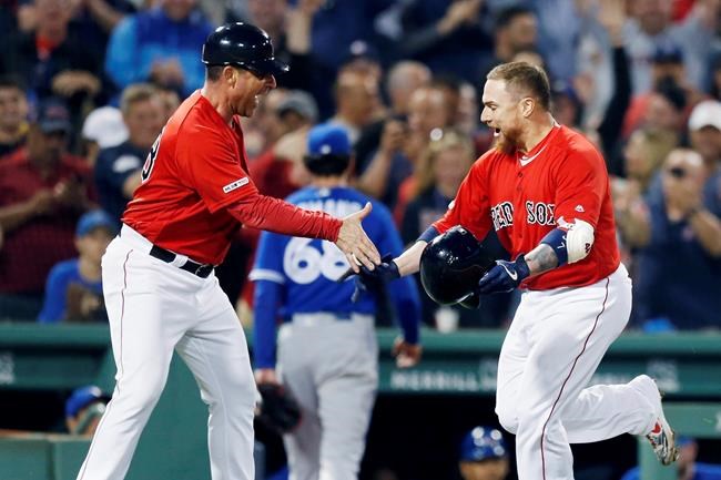 Boston Red Sox's Christian Vazquez, right, celebrates with third base coach Carlos Febles after hitting a walkoff home run as Toronto Blue Jays' Jordan Romano (68) enters the dugout during the 10th inning of a baseball game in Boston, Friday, June 21, 2019. (AP Photo/Michael Dwyer)