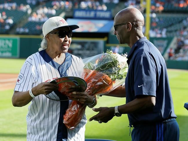 Minnie Forbes, former owner of the Detroit Stars of the Negro Leagues, is presented with flowers by former Detroit Tiger Jake Wood, right, during a celebration of the Negro Leagues before the Tigers' baseball game against the Kansas City Royals on Saturday, Aug. 10, 2019, in Detroit. (AP Photo/Duane Burleson)