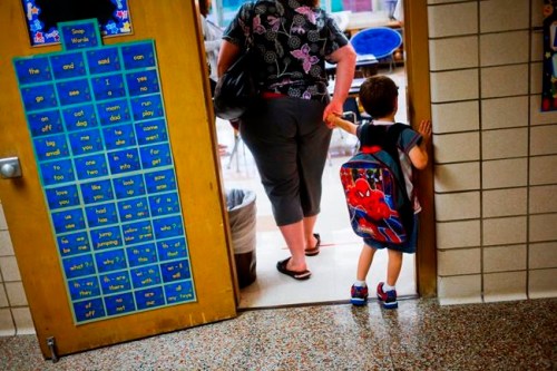 FILE - In this Sept. 8, 2015 file photo, a reluctant student is pulled into the first day of kindergarten at an elementary School in Clio, Mich. A study shows the youngest children in a classroom are more likely to be diagnosed with attention deficit hyperactivity disorder. It‚Äôs an intriguing finding for parents considering what‚Äôs called ‚Äúkindergarten redshirting,‚Äù or delaying school entry. Researchers say doctors should be aware of how classroom comparisons shape diagnosis. The paper was published Wednesday, Nov. 28, 2018, by the New England Journal of Medicine. (Christian Randolph/The Flint Journal via AP, File)