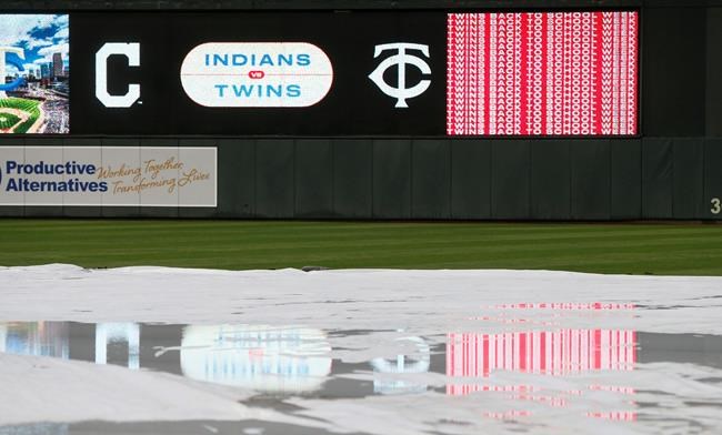 Puddles on a tarp reflect the scoreboard during a rain delay before the Minnesota Twins and the Cleveland Indians baseball game Saturday, Aug. 10, 2019, in Minneapolis. (AP Photo/Jim Mone)