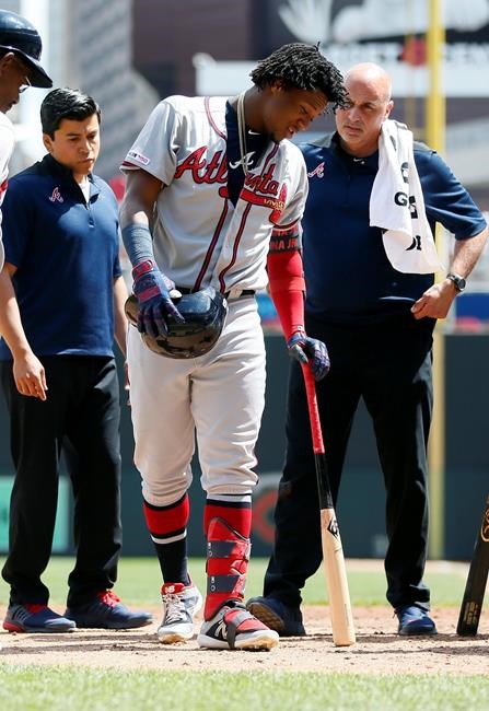 Atlanta Braves' Ronald Acuna Jr., center, leans on his bat as trainers watch after he fouled a ball off his leg in the sixth inning of a baseball game against the Minnesota Twins Wednesday, Aug. 7, 2019, in Minneapolis. (AP Photo/Jim Mone)