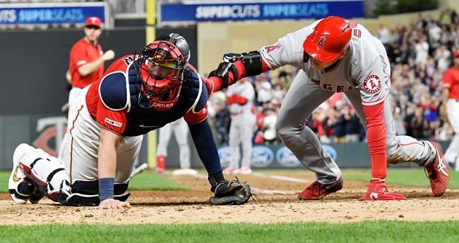 Los Angeles Angels' Shohei Ohtani, right, comes to the aid of Minnesota Twins' catcher Mitch Garver after Garver was injured tagging out Ohtani as he attempted to score from second base on a hit by Brian Goodwin in the eighth inning of a baseball game Tuesday, May 14, 2019, in Minneapolis. Garver was helped off the field. The Twins won 4-3. (AP Photo/Jim Mone)