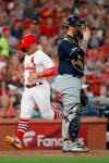 St. Louis Cardinals' Kolten Wong, left, scores past Milwaukee Brewers catcher Yasmani Grandal during the fifth inning of a baseball game Monday, Aug. 19, 2019, in St. Louis. (AP Photo/Jeff Roberson)