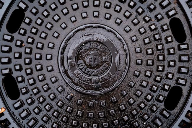 This Saturday, Nov. 2, 2019 photo, shows a manhole cover surviving from communist times in Berlin, when Volkseigene Betriebe, or Publicly Owned Enterprises, manufactured manhole covers for East German streets.(AP Photo/Markus Schreiber)