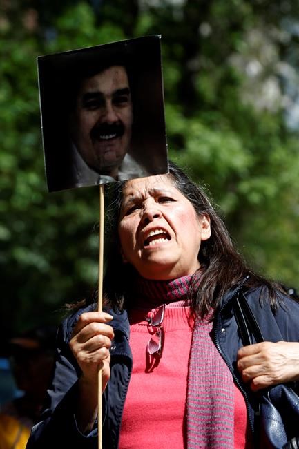 A supporter of Venezuelan President Nicolas Maduro holds a photo of Maduro during a protest in front of U.S. Embassy in Mexico City, Saturday Jan. 26, 2018. The United States is urging all nations to support Venezuelan opposition leader Juan Guaido even as Russia is accusing the Trump administration of attempting