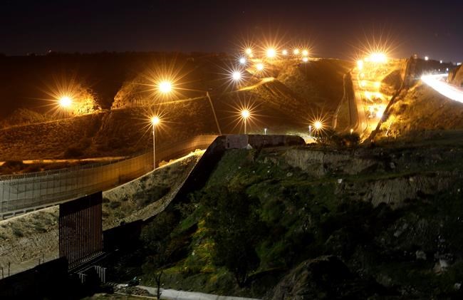 Floodlights from the U.S, illuminate multiple border walls Monday, Jan. 7, 2019, seen from Tijuana, Mexico. With no breakthrough in sight, President Donald Trump will argue his case to the nation Tuesday night that a