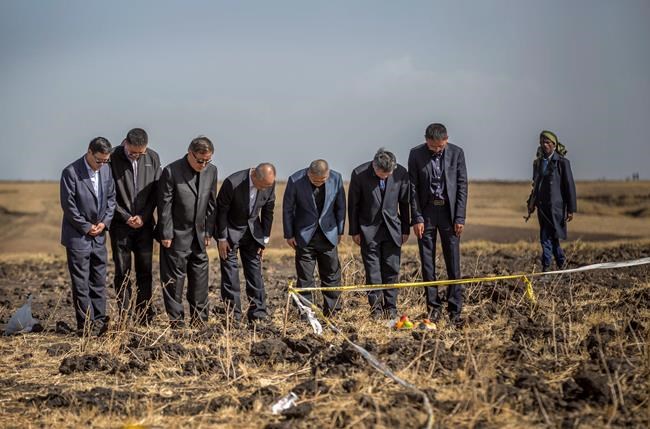Officials from the Aviation Industry Corporation of China (AVIC) pray next to an offering of fruit, bread rolls, and a plastic container of Ethiopian Injera, a fermented sourdough flatbread, placed next to incense sticks, at the scene where the Ethiopian Airlines Boeing 737 Max 8 crashed shortly after takeoff on Sunday killing all 157 on board, near Bishoftu, or Debre Zeit, south of Addis Ababa, in Ethiopia Tuesday, March 12, 2019. Ethiopian Airlines had issued no new updates on the crash as of late afternoon Tuesday as families around the world waited for answers, while a global team of investigators began picking through the rural crash site. (AP Photo/Mulugeta Ayene)