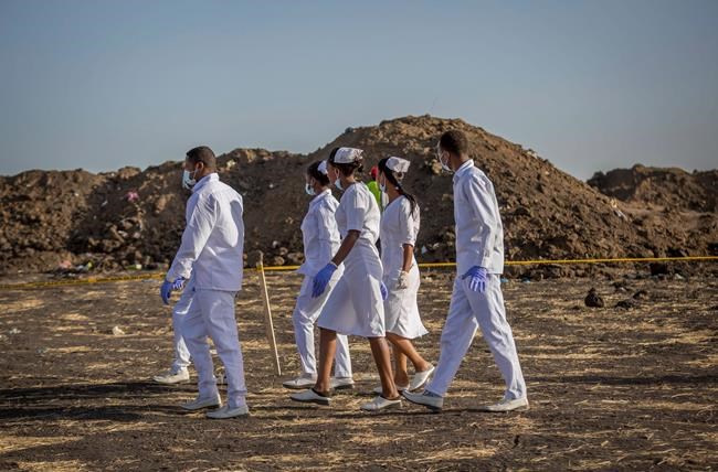 Nurses walk to collect materials, under the instruction of investigators, at the scene where the Ethiopian Airlines Boeing 737 Max 8 crashed shortly after takeoff on Sunday killing all 157 on board, near Bishoftu, or Debre Zeit, south of Addis Ababa, in Ethiopia Tuesday, March 12, 2019. (AP Photo/Mulugeta Ayene)