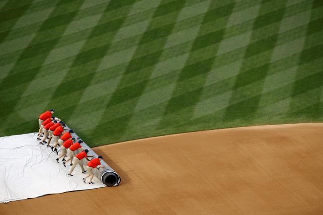 Grounds crew members roll a tarp over the infield during a rain delay before a baseball game between the Philadelphia Phillies and the Washington Nationals, Tuesday, June 18, 2019, in Washington. (AP Photo/Patrick Semansky)
