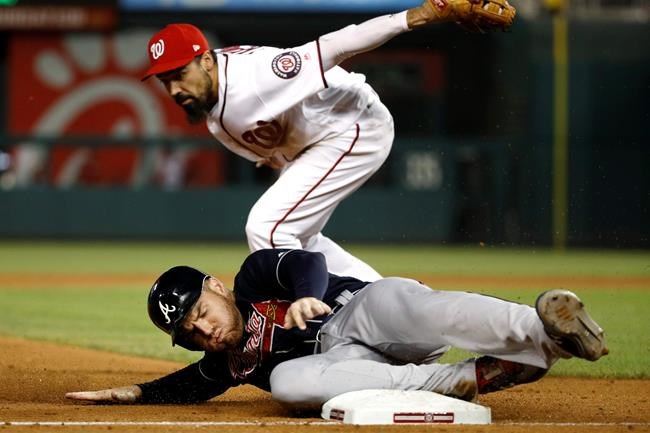 Atlanta Braves' Freddie Freeman, bottom, slides safely into third base past Washington Nationals third baseman Anthony Rendon on Josh Donaldson's single in the sixth inning of a baseball game, Monday, July 29, 2019, in Washington. (AP Photo/Patrick Semansky)