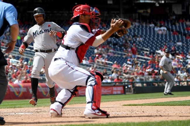 Miami Marlins' Starlin Castro, left, comes in to score on sacrifice fly by Miguel Rojas during the eighth inning of a baseball game against Washington Nationals catcher Kurt Suzuki, right, Monday, May 27, 2019, in Washington. (AP Photo/Nick Wass)
