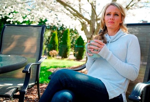 In this Wednesday, March 27, 2019, photo, Kacey Ruegsegger Johnson enjoys a coffee in a light spring breeze in the back yard of her home in Cary, N.C. For the last 20 years since she was injured in the Columbine High School attack, she has lived with post-traumatic stress disorder, along with physical pain. Now a mother of four, she has worked hard not to pass that fear on to her children. (AP Photo/Allen G. Breed)