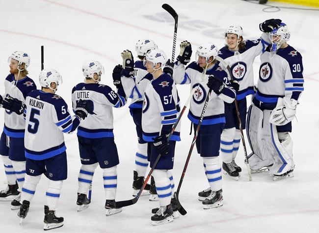 Winnipeg Jets goalie Laurent Brossoit (30) is congratulated by Sami Niku, of Finland, and other teammates following an NHL hockey game against the Carolina Hurricanes in Raleigh, N.C., Friday, March 8, 2019. (AP Photo/Gerry Broome)